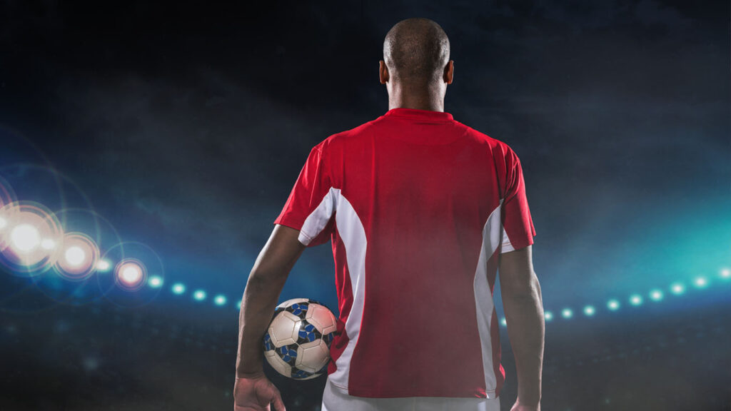 campeonatos internacionais: Jogador de futebol profissional com uma bola em pé no estádio, vista traseira