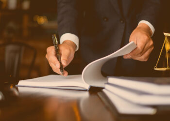 Fair play financeiro: Advogado assinando contrato ao lado de uma balança da justiça em miniatura