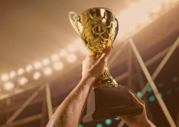 Times com mais títulos no Brasil: Atleta segurando a taça do troféu acima da cabeça no estádio