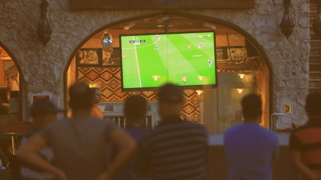 Pessoas assistindo jogo na televisão no qatar